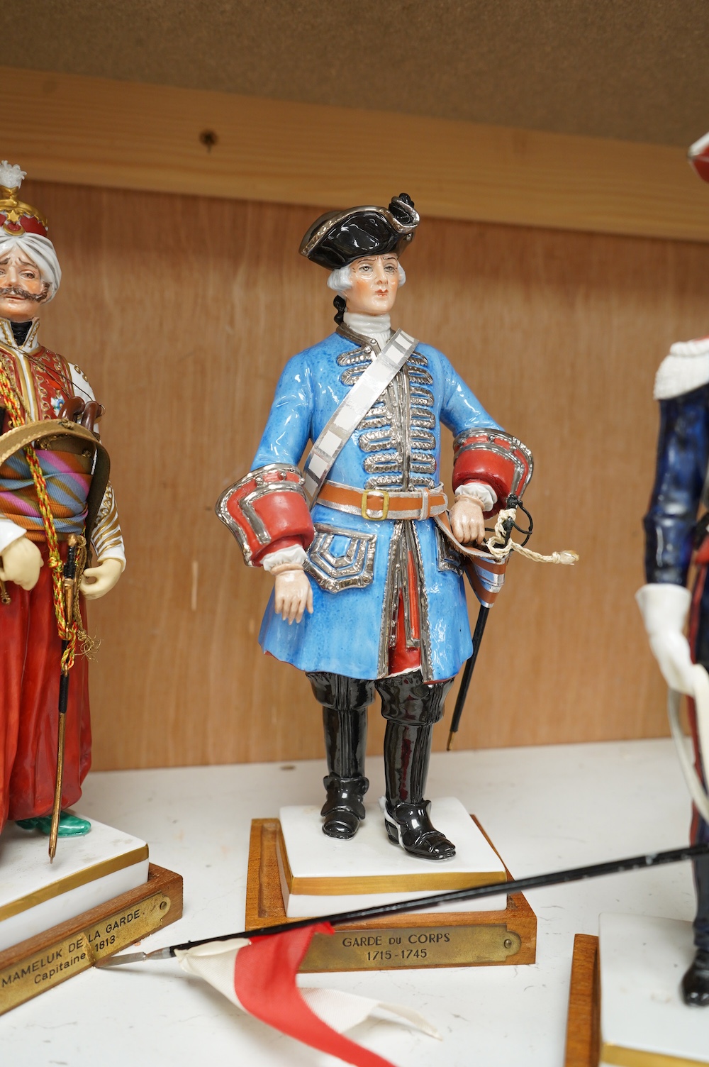 A set of four French porcelain military figures on stands to include ‘Hussards De Bercheny Officer’ and ‘Garde Du Corps’, largest 26cm high. Condition - mostly good condition with some minor losses